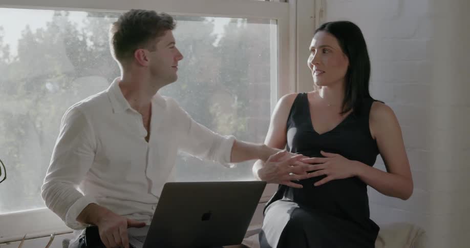 A woman looks out the window then leans to kiss a man