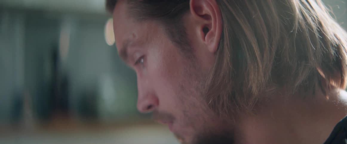 Close up profile of a sad young man looking down in deep thought.