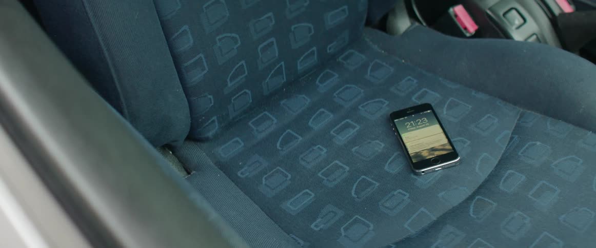 Close up shot of a smartphone lying alone on a patterned car passenger seat.