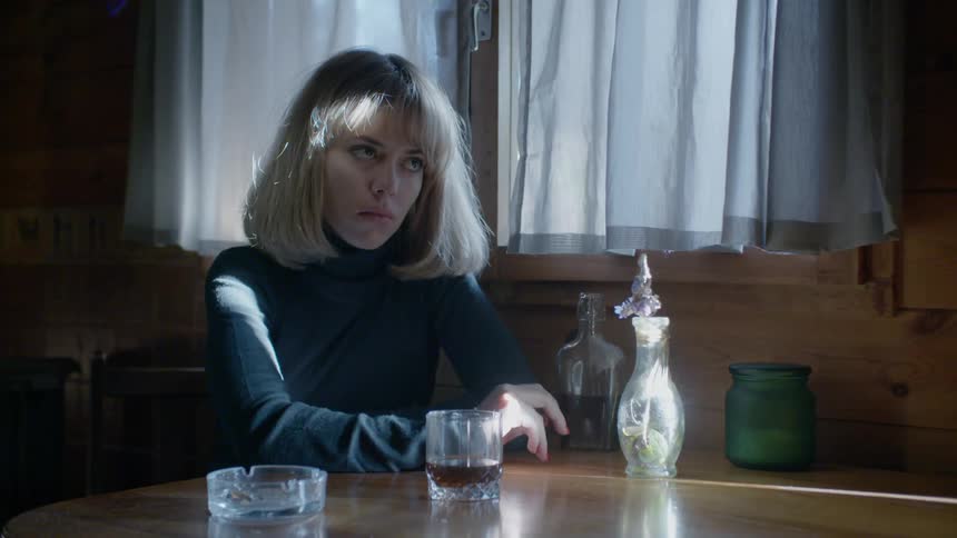 A woman sits at the table with a drink