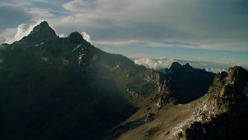 Mountains sit under a cloudy blue sky