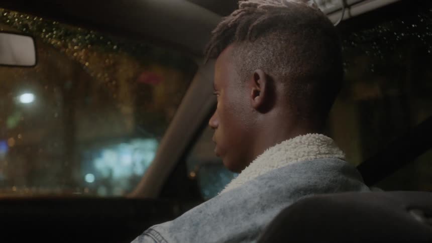 A man sits in the passenger seat as the car drives