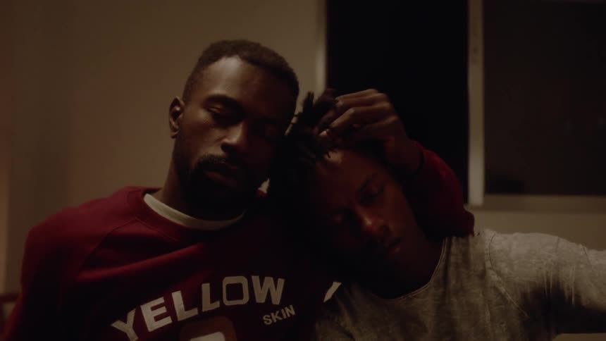 A man is rubbing the head of another man as he lays on his shoulder
