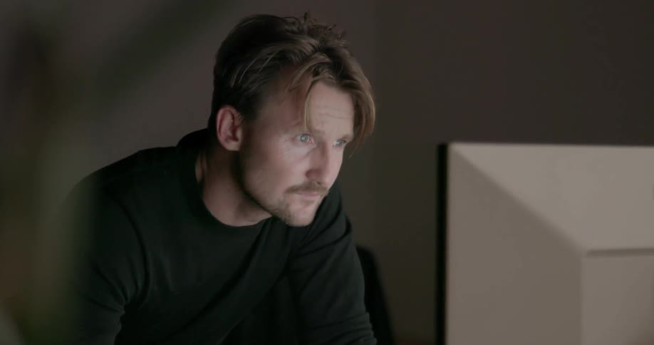 A man leans forward using a computer