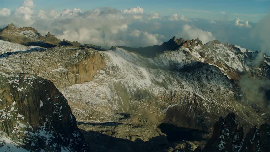 The mountains are touching the clouds, and are covered with snow