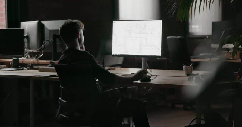 Man sits at desk looking at computer monitor
