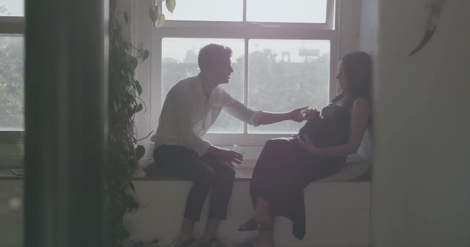 A man is rubbing a pregnant woman's belly