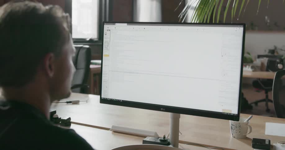 Man looks at a computer monitor while sitting at a desk