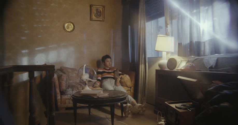 Woman sits in front of a table fan at home