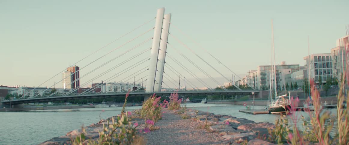 A gravel covered piece of land opens up to a large city scape with a bridge