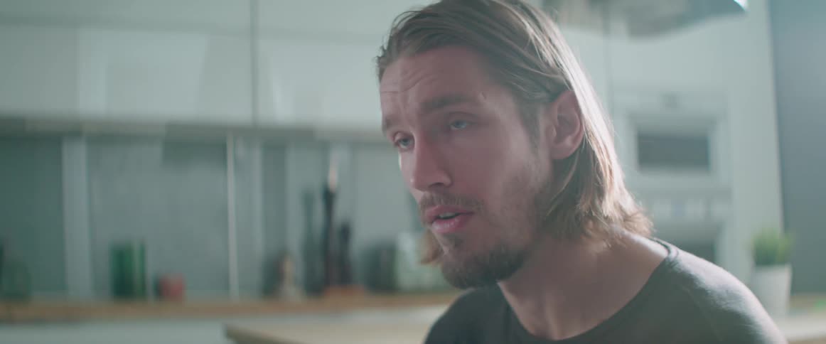 A frustrated guy explains something during an argument with someone in the kitchen.