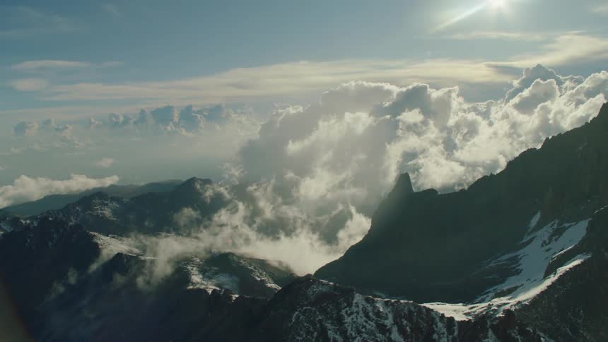 The clouds barely touch the top of the tall mountains