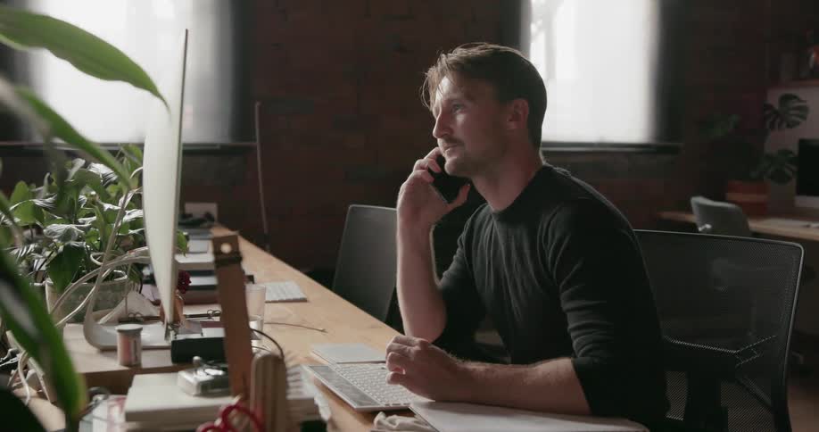 A man answers the phone while working in an office