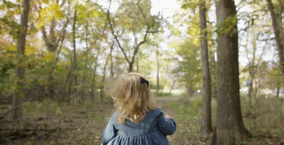 A woman carries a toddler on her shoulders in a forest