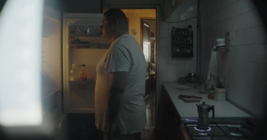 A man stands still in front of the open fridge