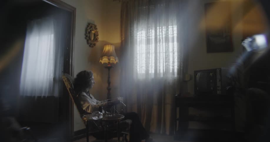 A woman sits in the rocking chair by the window