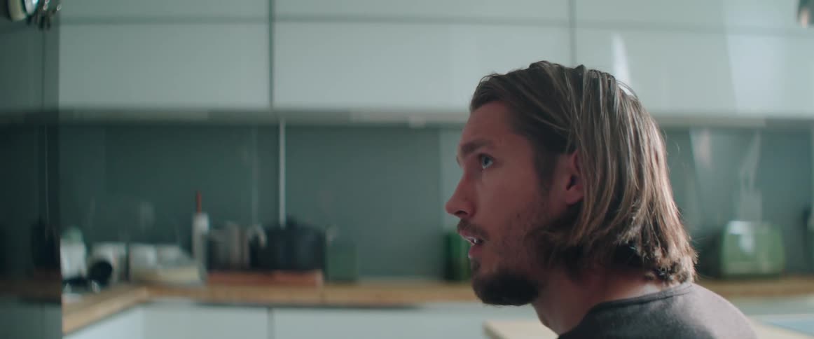 Profile shot of a frustrated young man talking to someone in a kitchen.