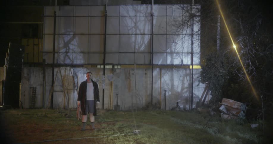 A man stands outside in his robe and pajamas