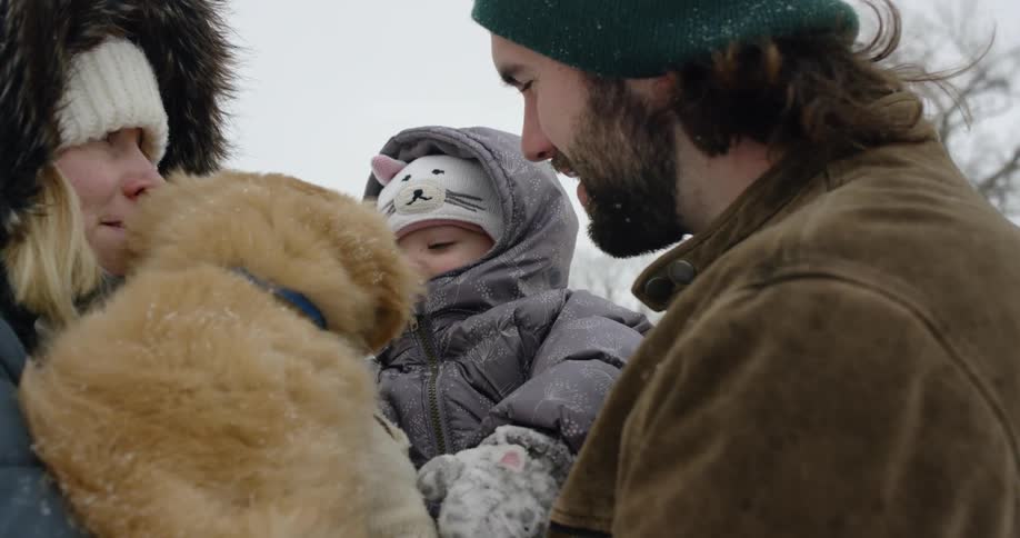 A woman holds a puppy up to a baby