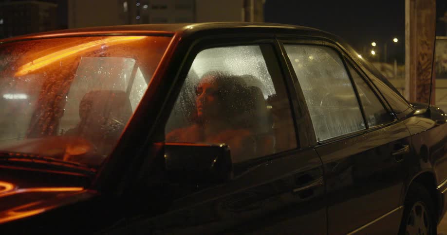 Woman sits in the driver's seat of a car at night