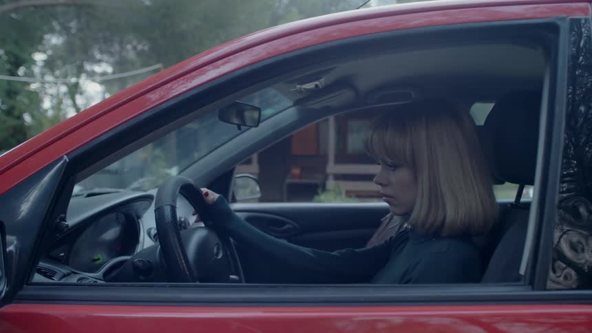 A woman sits in a parked car