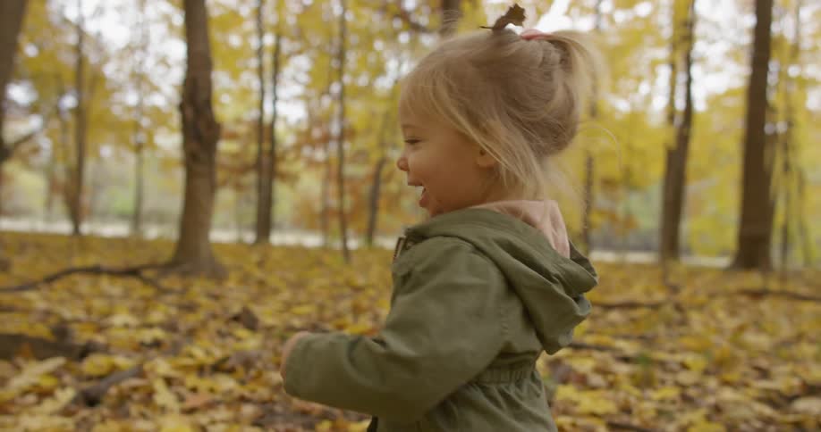 A toddler girl runs in a forest