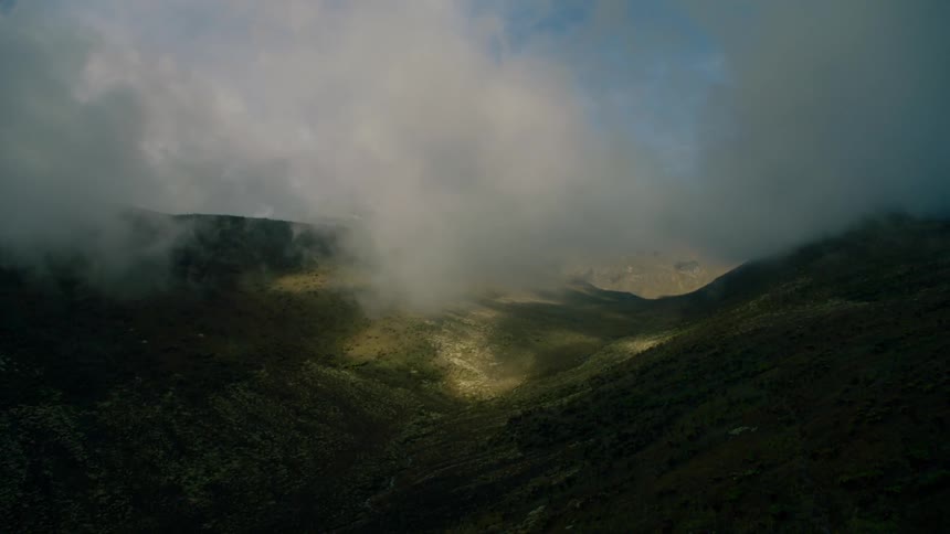 The green hills are covered with thick clouds