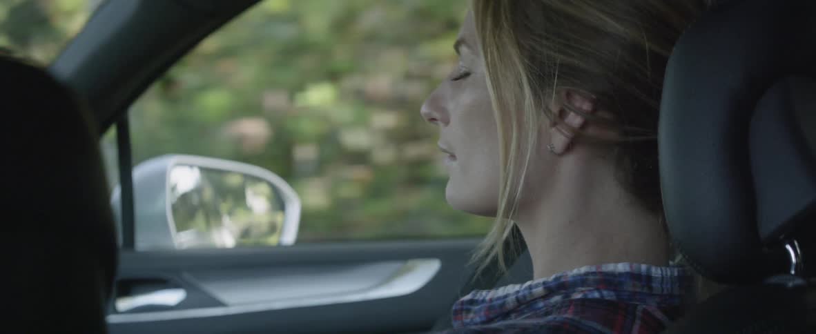 A woman rides in a car with her eyes closed