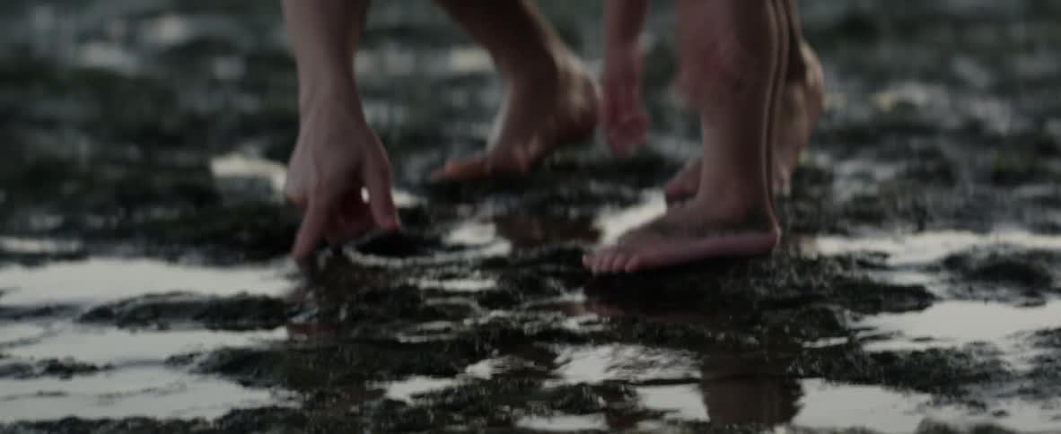 A father and son explore tide pools together as waves rush in along the shore