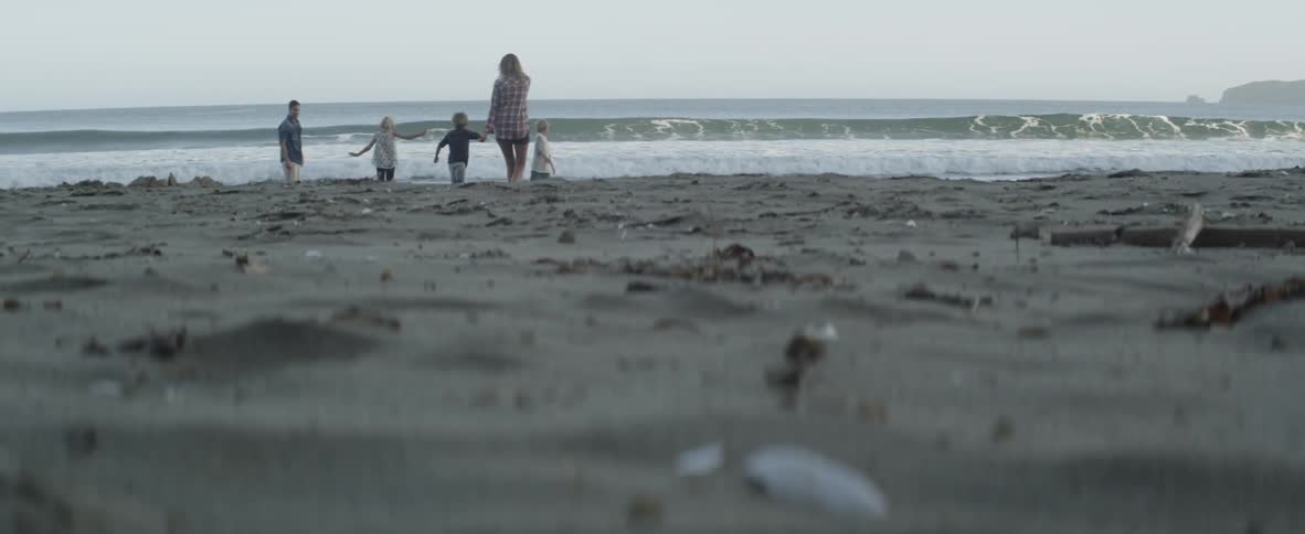 A family of five shares a joyful moment together on a wild, empty beach