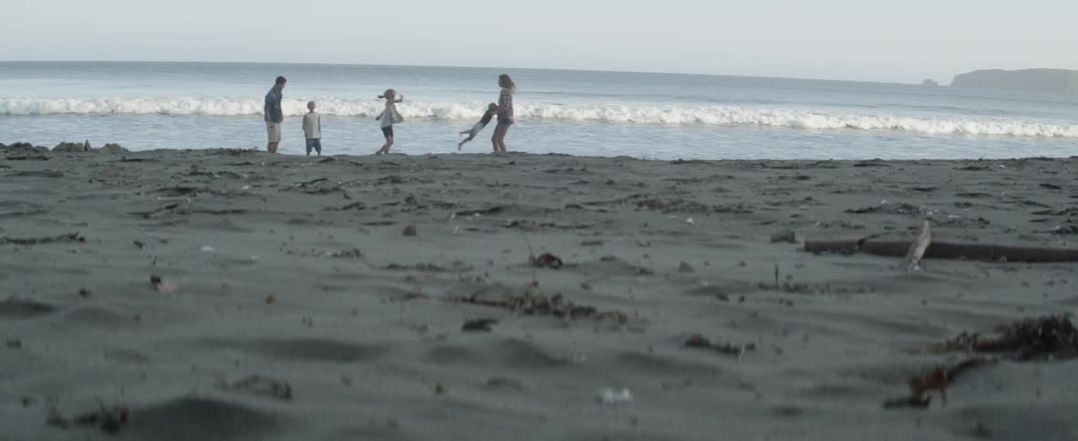 A family of five plays freely on a wild beach, alone with the waves