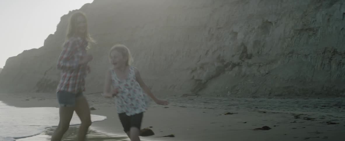 Woman chases a young girl on the beach
