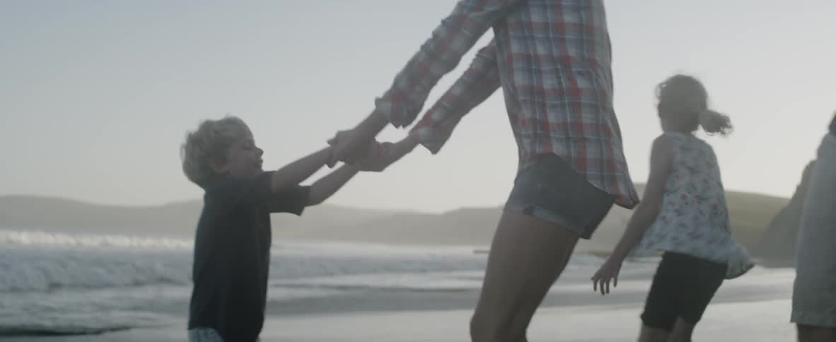 A woman plays with her children on the beach