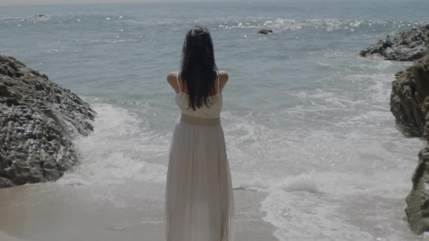 Woman standing at the edge of a beach