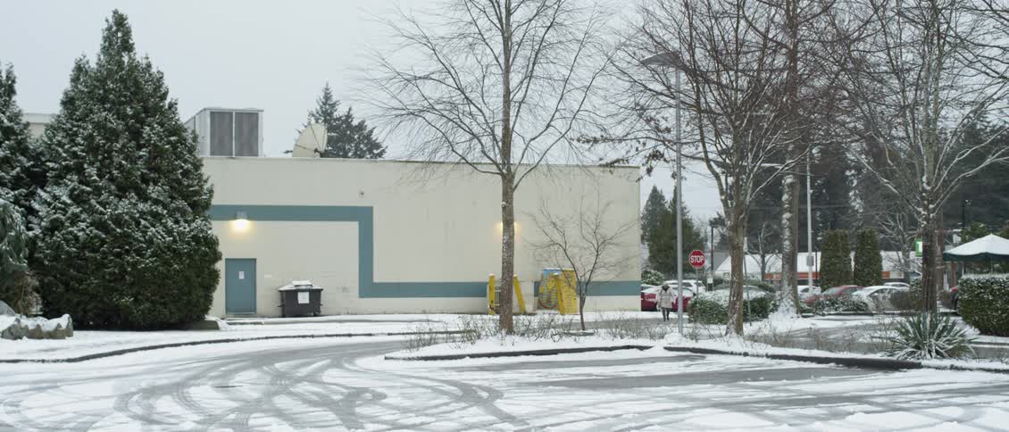 The parking lot is almost empty and is covered with snow