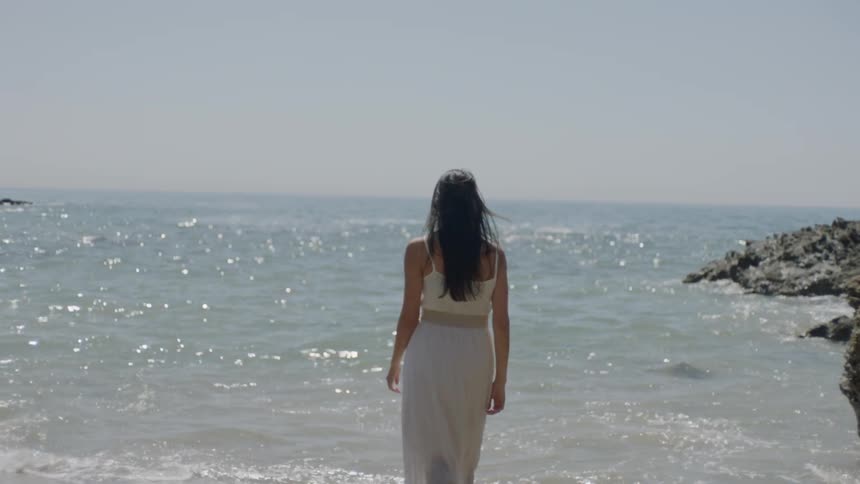 Woman wearing white walks into the ocean