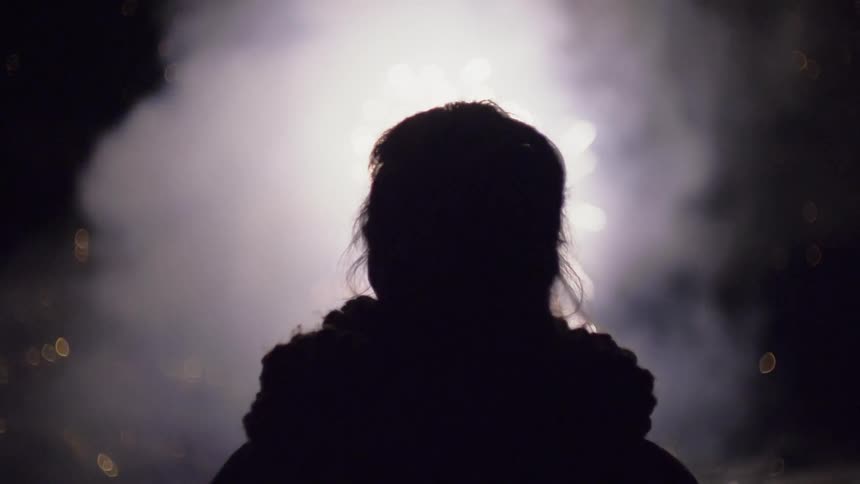 Woman watches fireworks in the dark sky