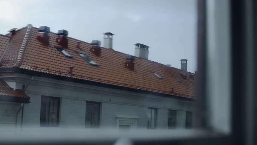 The rooftop of another building is visible through a window