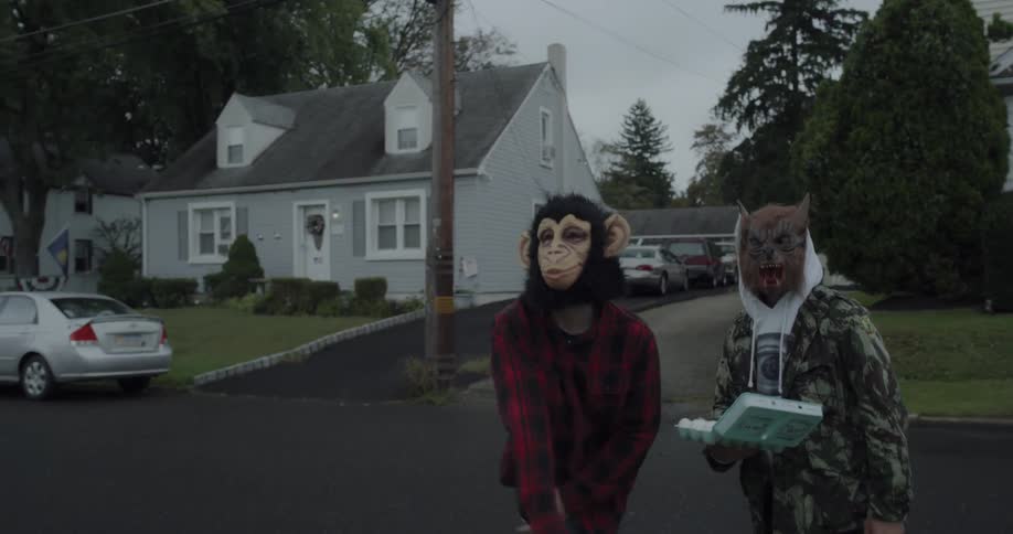 Two people with masks begin throwing eggs towards a house