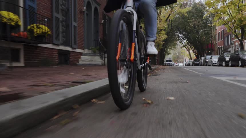 Person riding bicycle down neighborhood street in city