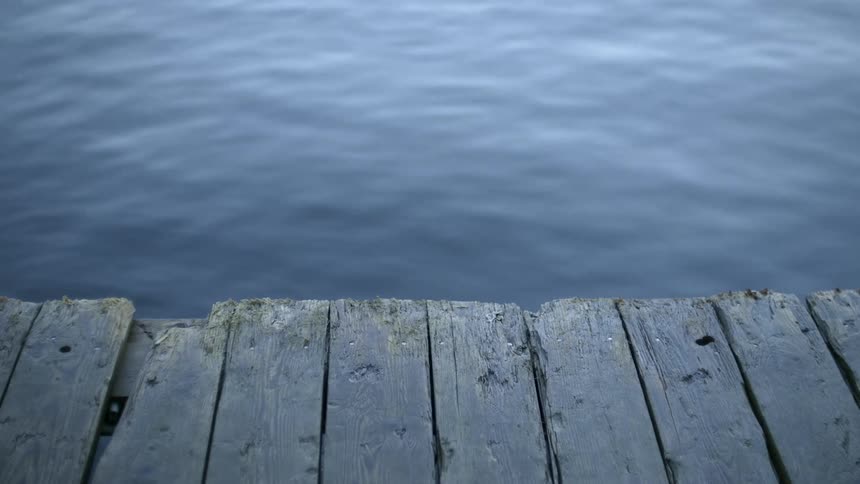 Body of water rippling next to a wooden deck