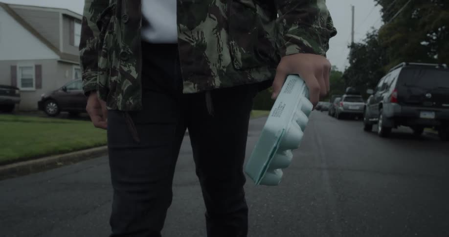 A man carries a carton of eggs on a residential street