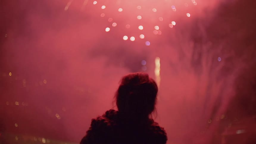A woman watches fireworks explode in the sky