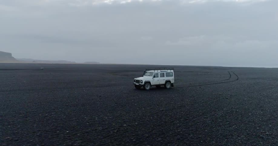 A jeep is driving over a black dirt field