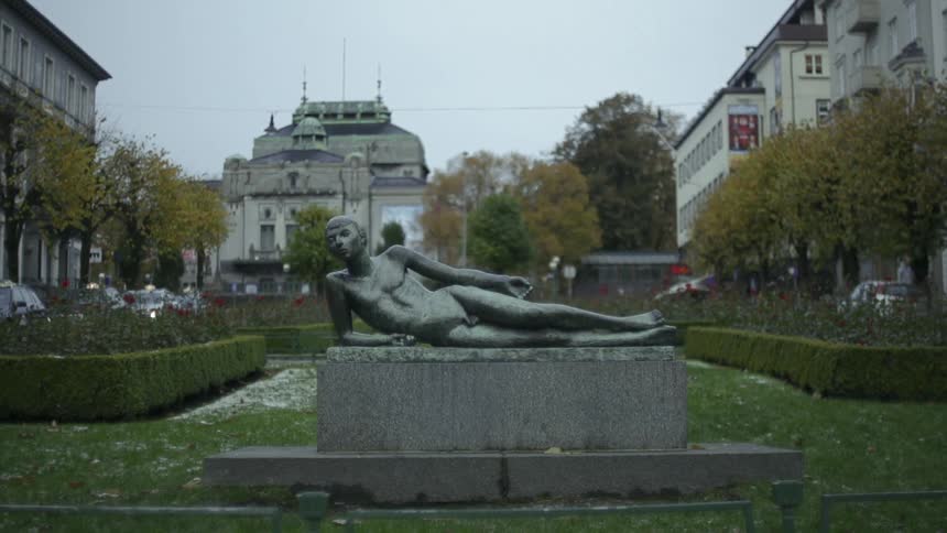 A statue of a naked man laying down on a slab of concrete