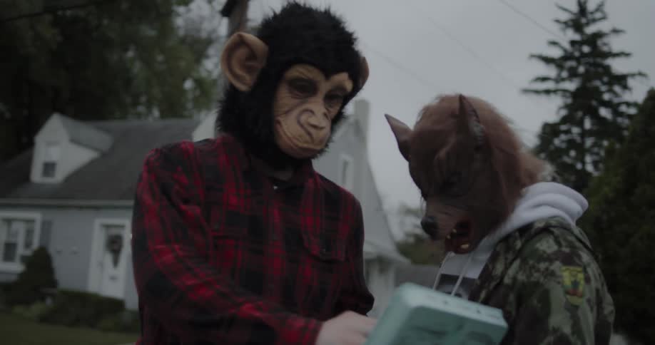 Two kids in halloween masks throw eggs on the street