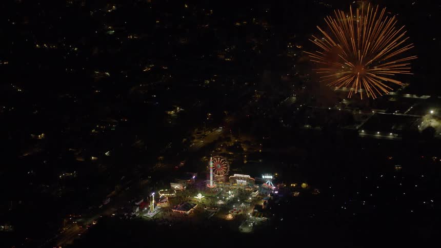 Fireworks going off over carnival in city at night