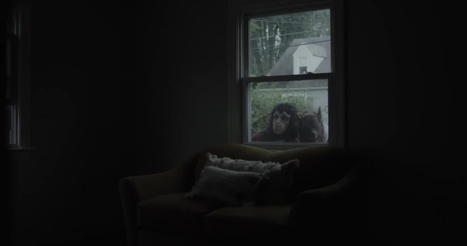 Teenagers in animal masks peek inside a house