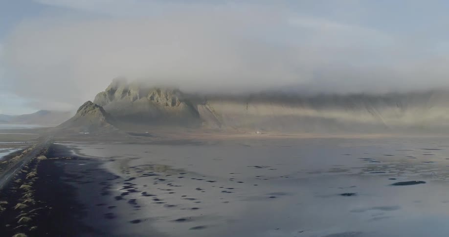 The mountain is tall and covered with a layer of clouds