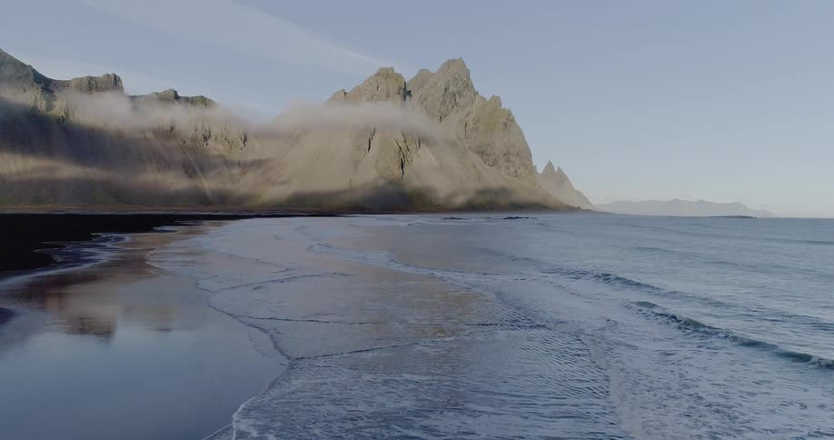 The shore leads to a mountain surrounded by clouds